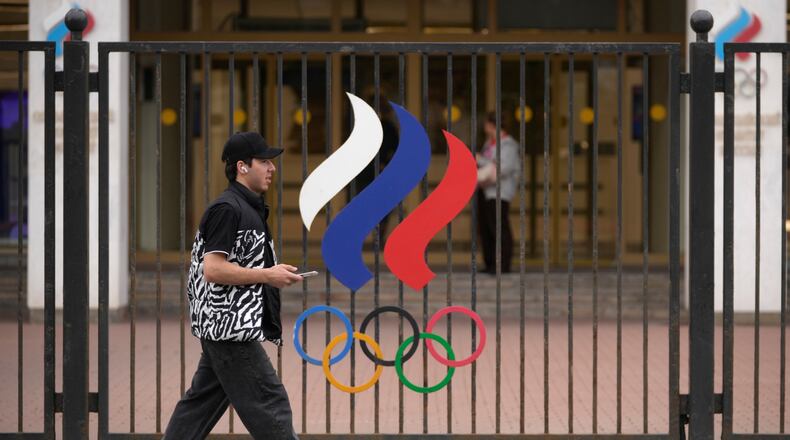 A man walks past a fence with Olympic Rings in front of the Russian National Olympic Committee building in Moscow, on Tuesday, July 7, 2026. (AP Photo/Pavel Bednyakov)