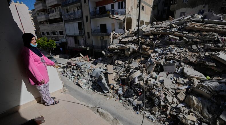 Em Ali Khodor, 75, looks through her damaged apartment into a destroyed building that was hit few weeks ago by an Israeli airstrikeafter she returns to the house, in the southern port city of Tyre, Lebanon, Thursday, April 30, 2026. (AP Photo/Hussein Malla)