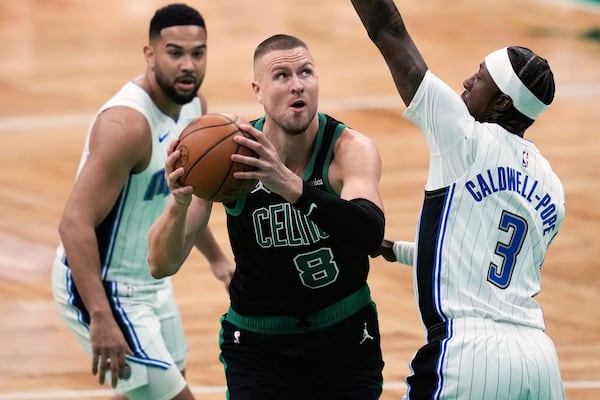 Boston Celtics center Kristaps Porzingis (8) drives to the basket against Orlando Magic guard Kentavious Caldwell-Pope (3) during the first half in game 5 of a first-round NBA playoff basketball series, Tuesday, April 29, 2025, in Boston. (AP Photo/Charles Krupa)