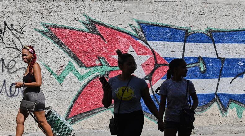People walk past graffiti in the colors of the Cuban flag in Havana, Cuba, Wednesday, June 17, 2026. (AP Photo/Jorge Luis Banos)