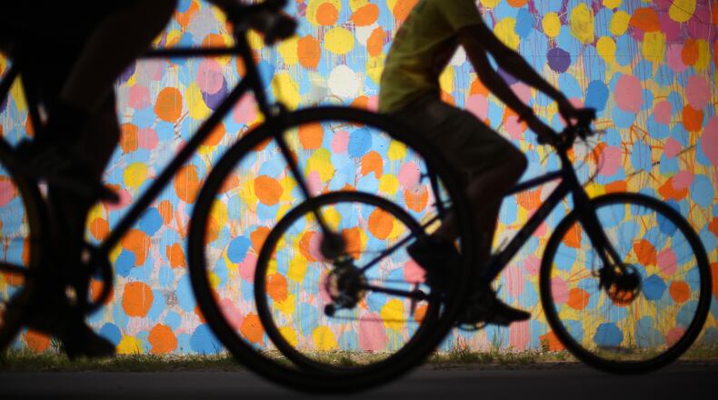 Bicyclists cruise along the Beltline past a mural by HENSE under Virginia Avenue. (Ben Gray / bgray@ajc.com)