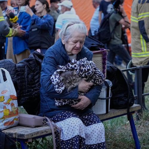 An elderly woman holds her car as she sits with her belongings in front of heavily damaged residential buildings after an overnight Russian attack, in Kyiv, Ukraine, Thursday, Aug. 20, 2026. (AP Photo/Efrem Lukatsky)