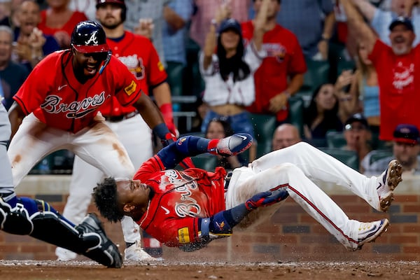 Ozzie Albies (supine) scores a run against the Brewers while Jorge Mateo watches. (Erik S. Lesser/AP)