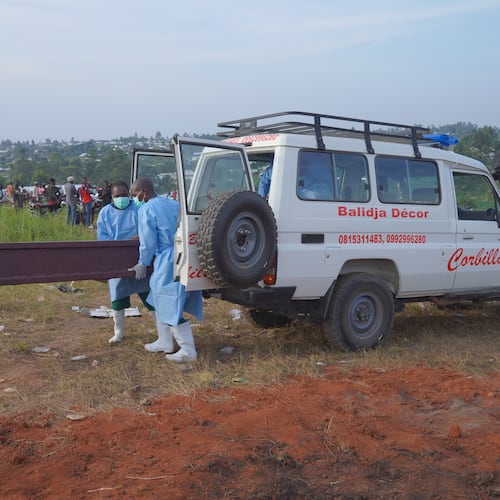 People dressed in protective gear unload a coffin containing the remains of six-year-old Baudjo Baraka Jules, who died of Ebola, for a burial service in Bunia, Ituri province, eastern Congo, Tuesday, Aug. 18, 2026. (AP Photo/Dieudonne Dirole)