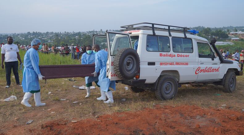 People dressed in protective gear unload a coffin containing the remains of six-year-old Baudjo Baraka Jules, who died of Ebola, for a burial service in Bunia, Ituri province, eastern Congo, Tuesday, Aug. 18, 2026. (AP Photo/Dieudonne Dirole)