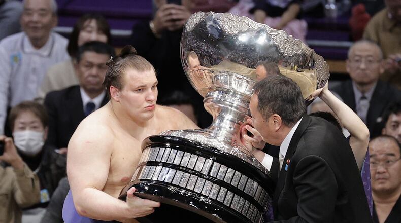 Ukrainian Aonishiki, left, receives a trophy after winning the Kyushu Grand Sumo Tournament in Fukuoka, western Japan, Sunday, Nov. 23, 2025. (Kyodo News via AP)
