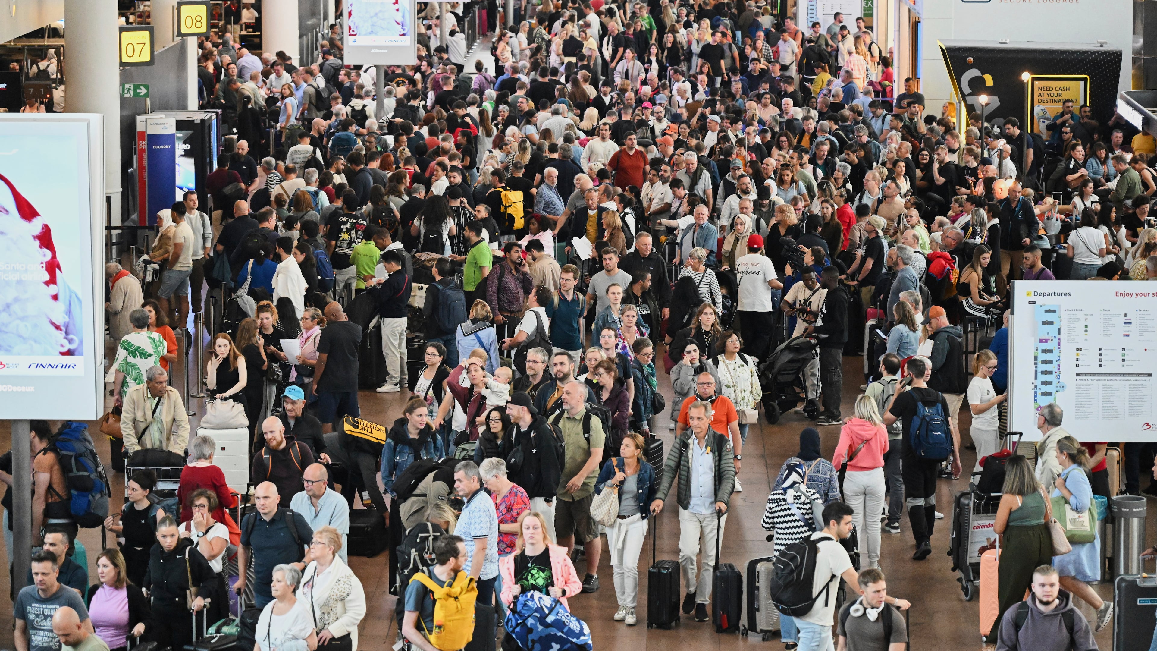 People walk by a departures board after a cyber attack caused delays at Brussels International Airport in Zaventem, Belgium, Saturday, Sept. 20, 2025. (AP Photo/Harry Nakos)