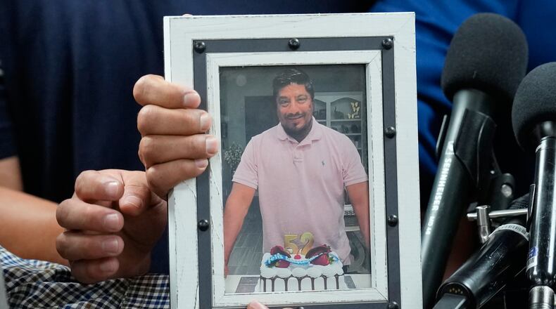 Ronaldo Salgado and Lorenzo Jr., sons of Lorenzo Salgado Araujo, hold a photograph of their father during a news conference Wednesday, July 8, 2026, in Houston. (AP Photo/David J. Phillip)