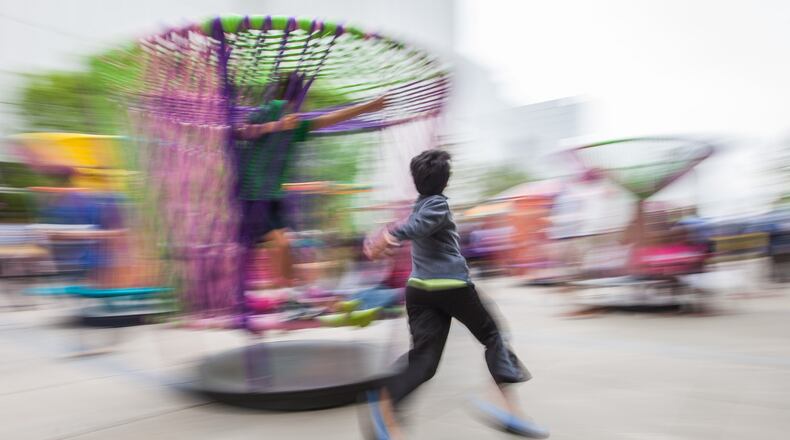 In this photo taken with a slow shutter speed, a boy runs around a large-scale spinning top full of children that is part of the High Museum of Art interactive art installation “Los Trompos” (“The Spinning Tops”), by Mexican designers Hector Esrawe and Ignacio Cadena. BRANDEN CAMP / SPECIAL