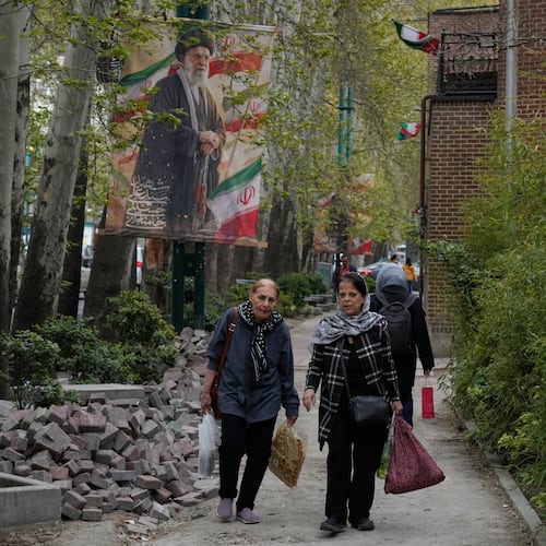 Women walk past a banner depicting the late Iranian Supreme Leader Ayatollah Ali Khamenei, who was killed in the U.S. and Israel strikes on Feb. 28, in northern Tehran, Iran, Sunday, April 12, 2026. (AP Photo/Vahid Salemi)