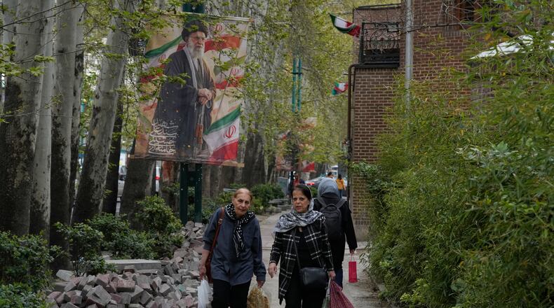 Women walk past a banner depicting the late Iranian Supreme Leader Ayatollah Ali Khamenei, who was killed in the U.S. and Israel strikes on Feb. 28, in northern Tehran, Iran, Sunday, April 12, 2026. (AP Photo/Vahid Salemi)