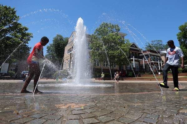 Jimmy Kupolati (left) and his brother, Victor, stay cool in the water fountain at the Duluth Town Green. As global temperatures climb, it increases the likelihood of extreme heat in Georgia, too. (Jason Getz/AJC 2024)