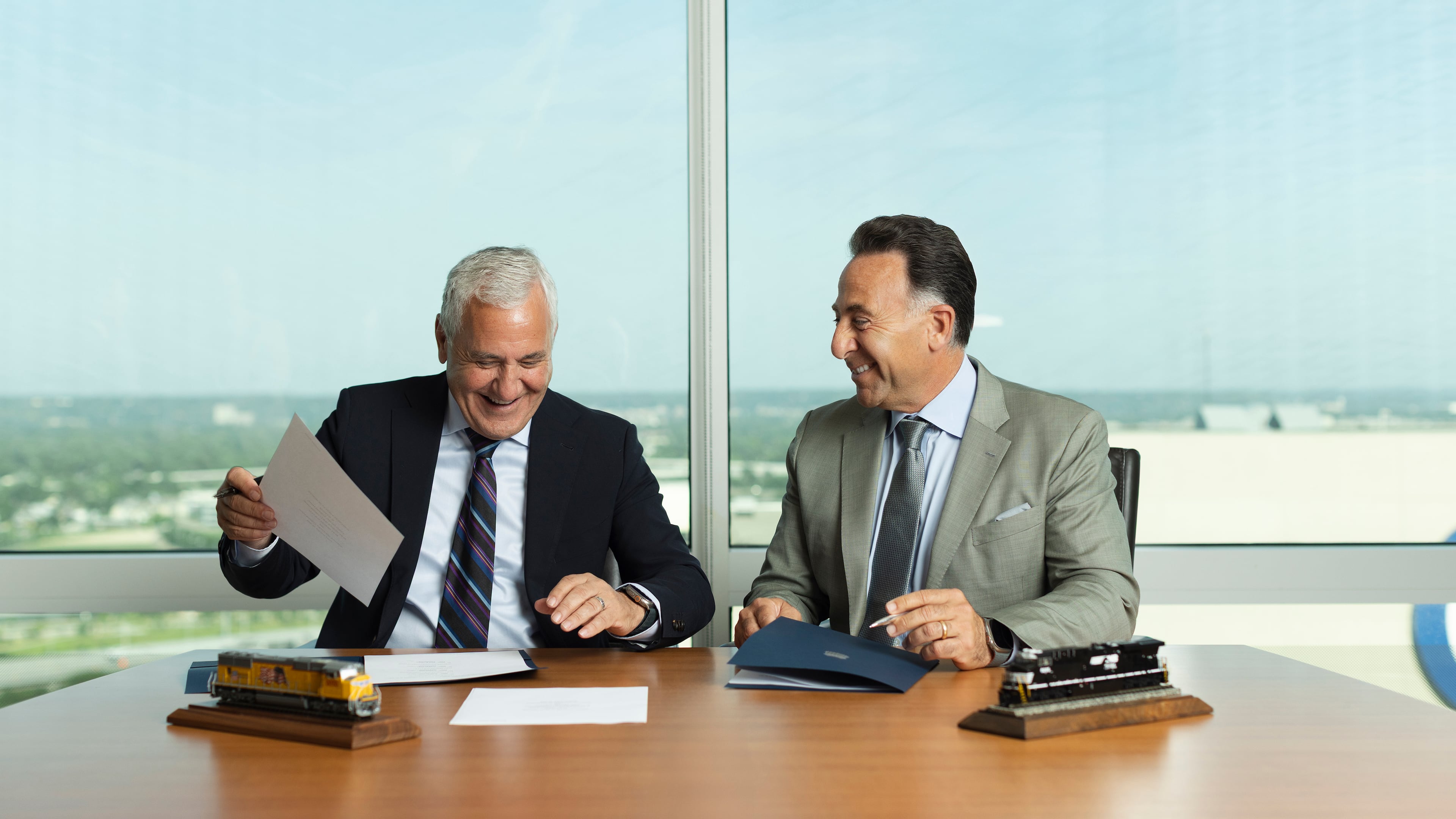 In this photo provided by Union Pacific, Union Pacific CEO Jim Vena (left) and Norfolk Southern CEO Mark George sign the agreement to merge the two railroads they lead on Monday, July 28, 2025, in Omaha, Neb. (Bill Sitzmann/Union Pacific via AP)