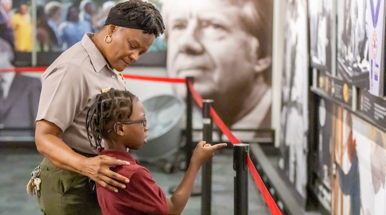 Superintendent of Martin Luther King, Jr. National Historical Park Judy Forte talks with Andre Thomas,7, about the images in the exhibit at the king Center that shows the connection between MLK and President Carter Tuesday, Feb. 28, 2023.  (Steve Schaefer/steve.schaefer@ajc.com)