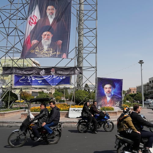 People drive their motorbikes past billboards showing the Iran's Supreme Leader Ayatollah Mojtaba Khamenei, top and right, and his father, the slain Supreme Leader Ayatollah Ali Khamenei, who was killed in U.S. and Israeli strikes on Feb. 28, in downtown Tehran, Iran, Thursday, April 16, 2026. (AP Photo/Vahid Salemi)