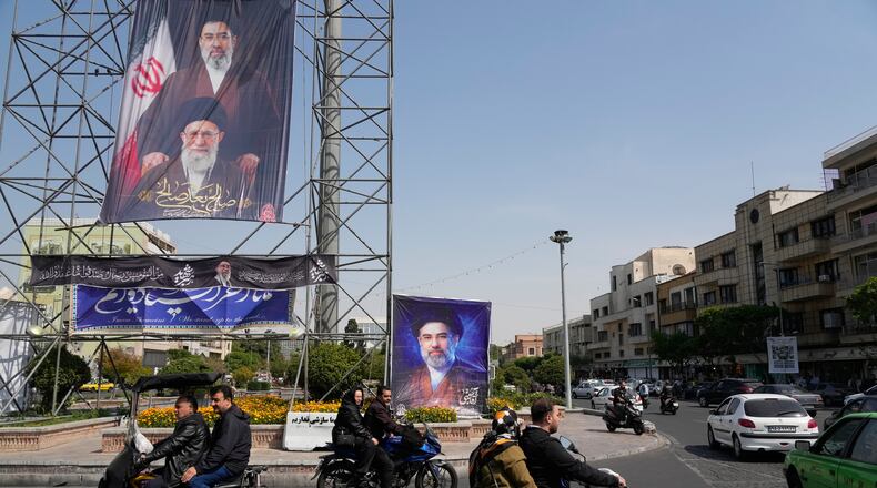 People drive their motorbikes past billboards showing the Iran's Supreme Leader Ayatollah Mojtaba Khamenei, top and right, and his father, the slain Supreme Leader Ayatollah Ali Khamenei, who was killed in U.S. and Israeli strikes on Feb. 28, in downtown Tehran, Iran, Thursday, April 16, 2026. (AP Photo/Vahid Salemi)