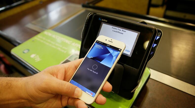 FILE - In this photo taken Friday, Oct. 17, 2014, Eddy Cue, Apple Senior Vice President of Internet Software and Services, demonstrates the new Apple Pay mobile payment system at a Whole Foods store in Cupertino, Calif. Apple on June 8, 2015 said that its adding store-issued credit cards and store rewards programs to Apple Pay, the mobile payments service it launched last fall. (AP Photo/Eric Risberg, File)