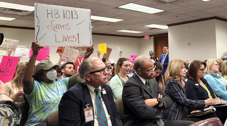 Supporters and opponents of a bill aiming to overhaul mental health care in Georgia hold signs during a Senate committee meeting. Maya T. Prabhu/maya.prabhu@ajc.com