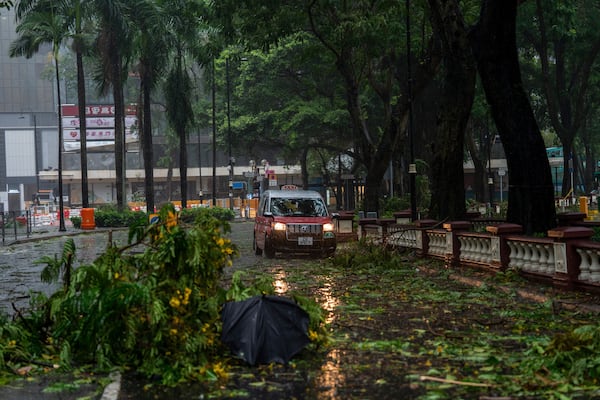 A taxi drives near fallen trees following the Typhoon Wipha, in Hong Kong, Sunday, July 20, 2025. (AP Photo/Vernon Yuen)