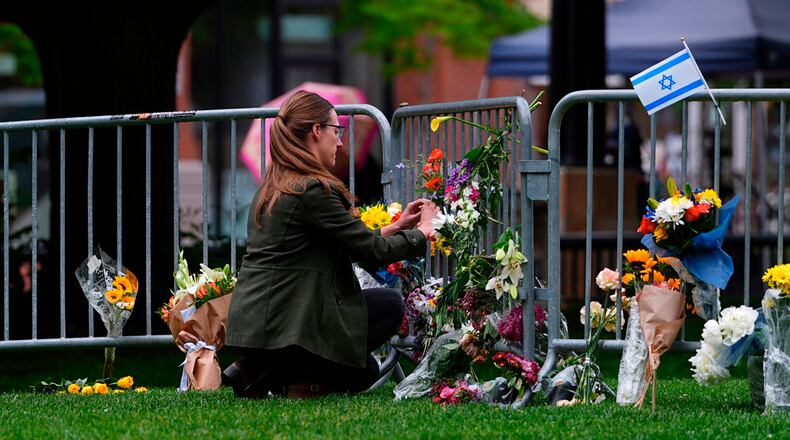 FILE - A woman places a bouquet of flowers at a makeshift memorial for victims of an attack outside of the Boulder County, Colo., courthouse Tuesday, June 3, 2025, in Boulder, Colo. (AP Photo/David Zalubowski, File)