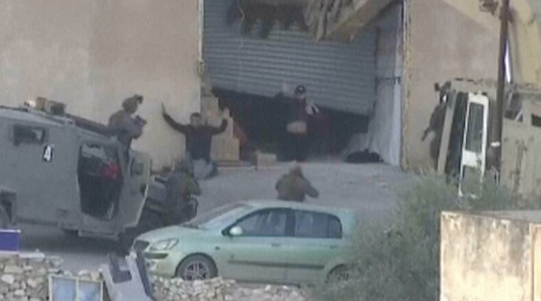 This image taken from video by Palestine TV shows two Palestinian men kneeling on the ground to Israeli forces shortly before they were shot dead during a military operation in Jenin, West Bank, on Thursday, Nov. 27, 2025. (Palestine TV via AP)