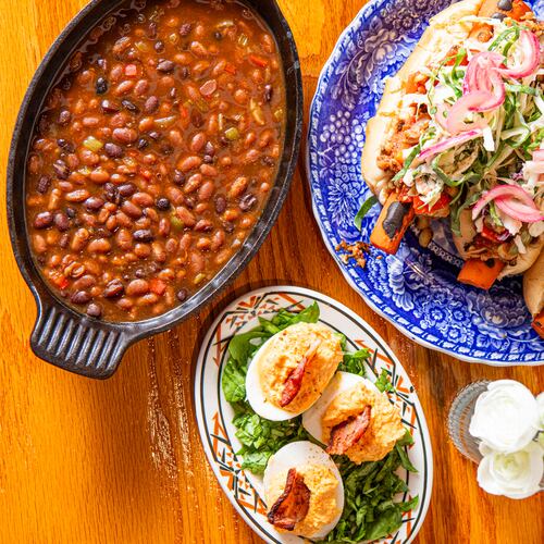 Michele Tompkins of Roots & Culture Craft Kitchen offers vegetable-forward recipes for your Labor Day celebration. Clockwise from top left: Two Bean Baked Beans, Loaded Carrot "Hot Dogs" and Sweet Potato Deviled Eggs with Candied Bacon Chips. (Aaliyah Man for the AJC/food styling by Michele Tompkins)