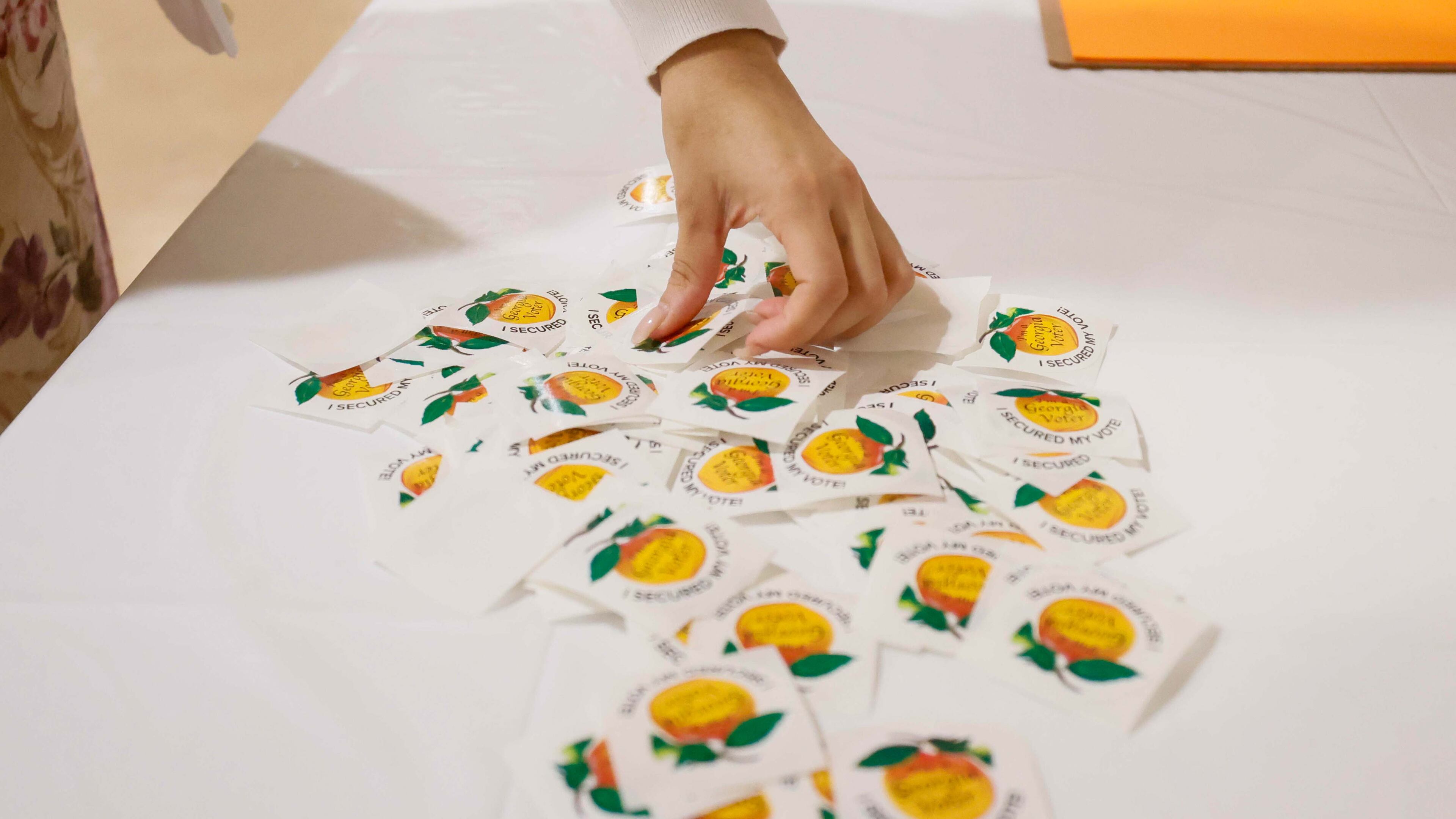 Fulton County resident Andrea Martinez picks a sticker after casting her ballot inside Antioch Baptist Church in Atlanta on Election Day. (Miguel Martinez/AJC 2024)