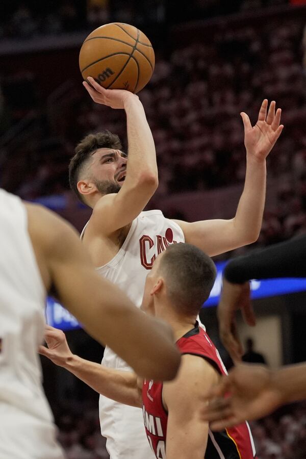 Cleveland Cavaliers guard Ty Jerome, left, shoots over Miami Heat guard Tyler Herro, front, in the second half in Game 1 of an NBA first-round playoff series, Sunday, April 20, 2025, in Cleveland. (AP Photo/Sue Ogrocki)