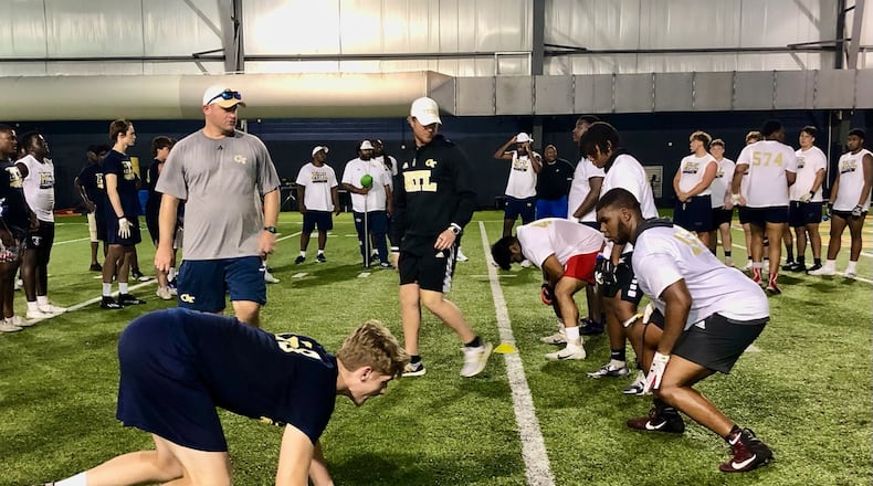 Hillgrove High offensive lineman Ben Galloway (white T-shirt) lines up for a practice repetition at Georgia Tech's prospect camp June 9, 2022. Tech offensive-line coach Brent Key (gray T-shirt) observes. (AJC photo by Ken Sugiura)
