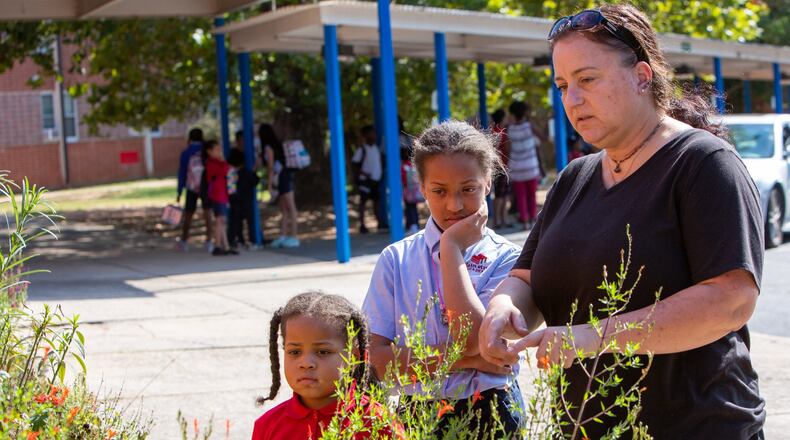 Teacher Nathan Strange (right) shows kindergartener Andrea Welmaker and sixth-grader Alaina Welmaker around one of the gardens at The Main Street Academy in College Park. CONTRIBUTED BY PHIL SKINNER