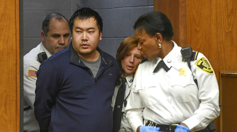 Jeffrey Yao, in blue, is escorted into Woburn District Court, Monday, Feb. 26, 2018 in Woburn, Mass. Yao was arraigned on charges of murder and attempted murder after allegedly stabbing medical student Deane Stryker, 22, to death Saturday, Feb. 24, at the Winchester Public Library. Yao is also accused of stabbing a 77-year-old man who rushed to Stryker's aid.
