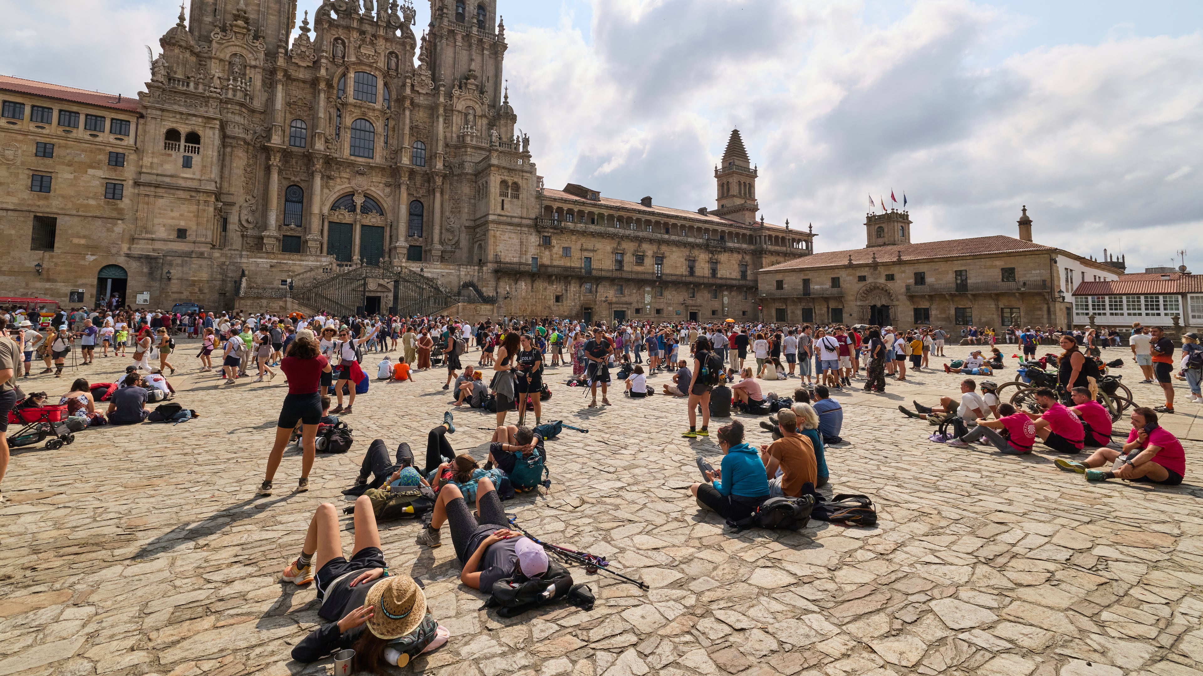 Pilgrims and tourists rest in front of the cathedral in Santiago de Compostela, northwestern Spain, Thursday, Aug. 21, 2025. (AP Photo/Lalo Villar)
