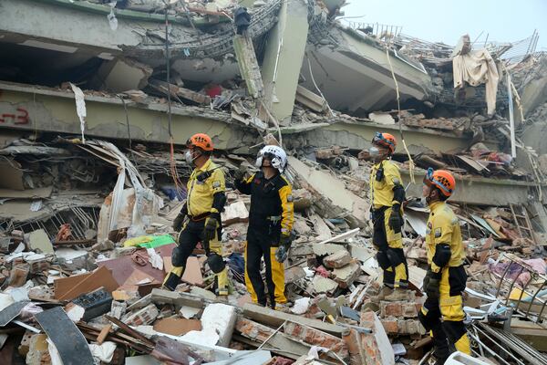 In this photo released by Xinhua News Agency, Chinese rescuers looks at a collapsed building before conducting a search and rescue operation in the aftermath of an earthquake in Mandalay, Myanmar, Sunday, March 30, 2025. (Myo Kyaw Soe/Xinhua via AP)