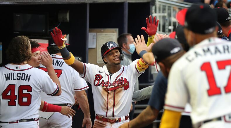 Braves outfielder Ronald Acuna gets high fives in the dugout hitting a solo home run to take a 2-0 lead over the Toronto Blue Jays during the third inning Tuesday, May 11, 2021, in Atlanta. (Curtis Compton / Curtis.Compton@ajc.com)