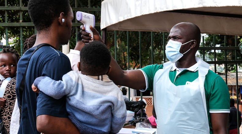 A health official uses a thermometer to screen people in front of Kibuli Muslim Hospital in Kampala, Uganda, Saturday, May 16, 2026. (AP Photo/ Hajarah Nalwadda)