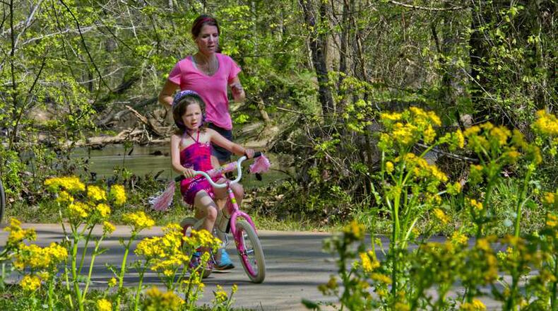 Grace Lochman (front) rides her bike as her mother, Nancy, runs next to her on the Big Creek Greenway in Alpharetta, on the Fulton County portion of the trail. JONATHAN PHILLIPS / SPECIAL