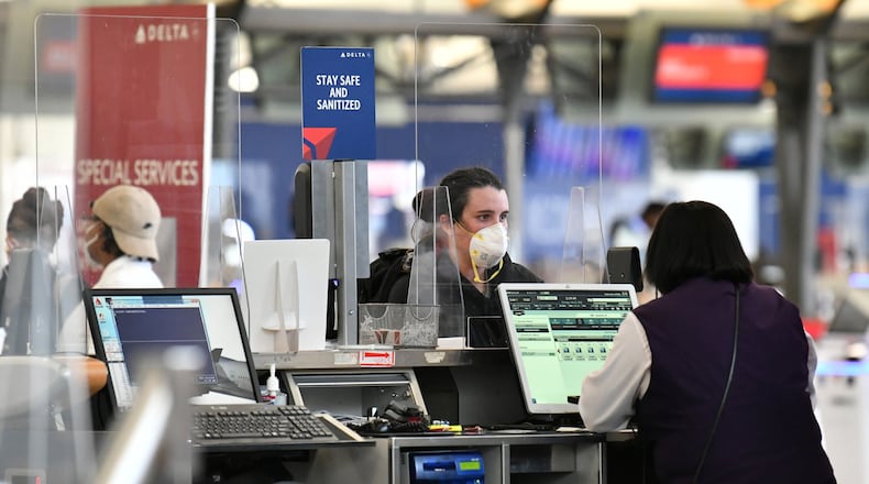 Travelers check in through plexiglass dividers at Delta at Hartsfield-Jackson. (Hyosub Shin / Hyosub.Shin@ajc.com)