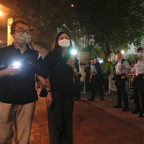 FILE - People hold candles walk past police officers near Hong Kong Victoria Park, a place in the past years for people to gather during a candlelight vigil to mark the anniversary of the military crackdown on a pro-democracy student movement in Beijing, in Hong Kong, on June 4, 2021. (AP Photo/Vincent Yu, File)