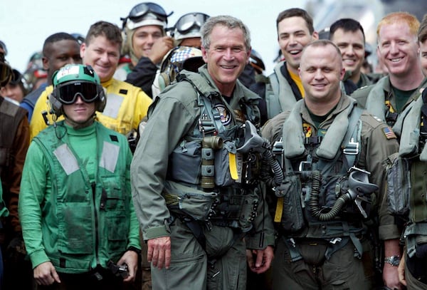 FILE - President George W. Bush poses with sailors and pilots aboard the USS Abraham Lincoln off the California coast after landing in a small jet May 1, 2003. (AP Photo/J. Scott Applewhite, File)