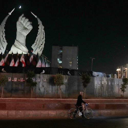 A man carries his bicycle in front of a monument depicting the clenched fist of the late Iranian Supreme Leader Ayatollah Ali Khamenei, who was killed in the U.S. and Israel strike on Feb. 28, in Islamic Revolution Square in Tehran, Sunday, July 19, 2026. (AP Photo/Vahid Salemi)