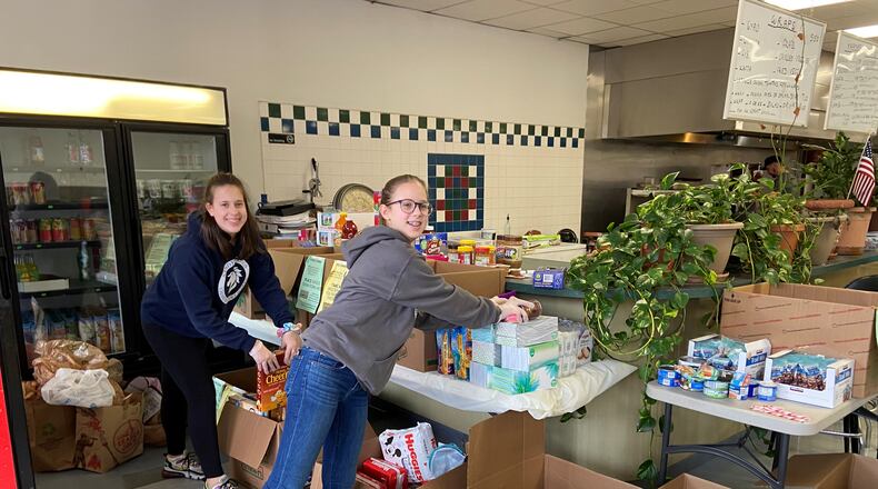 Georgia Alford and Winnie Alford, who are eighth and seventh graders at Sandy Springs Charter Middle School, respectively, place donated items for the community at Samad Mediterranean Grill and Market.  Photo courtesy Jennifer Lott
