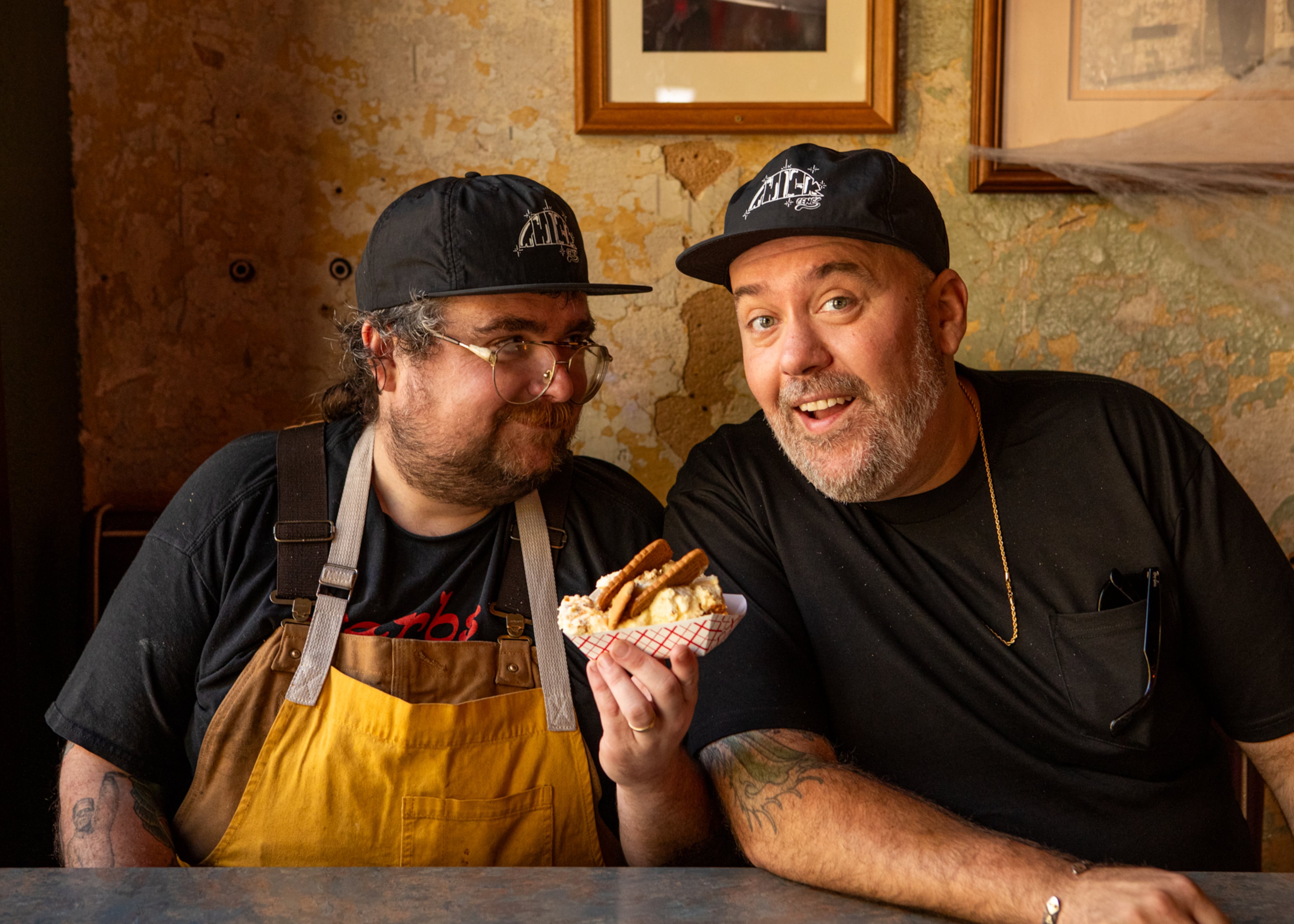 A year after Avery Cottrell’s (left) pop-up debuted as a brick-and-mortar in East Lake, Gene’s has established itself as a destination for eclectic barbecue and goofy vibes. Here, Cottrell and co-owner Matt Christensen show off the restaurant's popular Biscoff Banana Pud-Pud. (Aaliyah Man for the AJC)