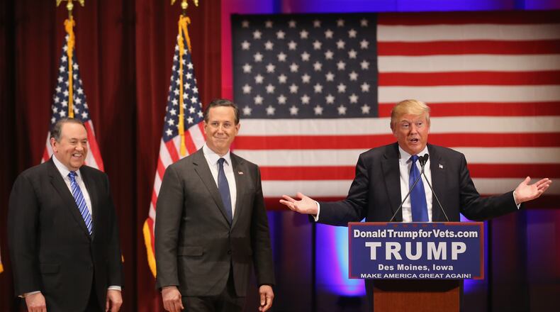 Republican presidential candidate Donald Trump, right, talks as rival candidates Mike Huckabee, left, and Rick Santorum attend the rally for veterans at Drake University on Thursday in Des Moines, Iowa. Christopher Furlong/Getty Images