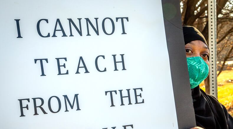 Teacher Amber Horton holds up a sign during a protest in front of the DeKalb school district offices along Mountain Industrial Boulevard in Stone Mountain on Dec. 29, 2020.  STEVE SCHAEFER FOR THE ATLANTA JOURNAL-CONSTITUTION