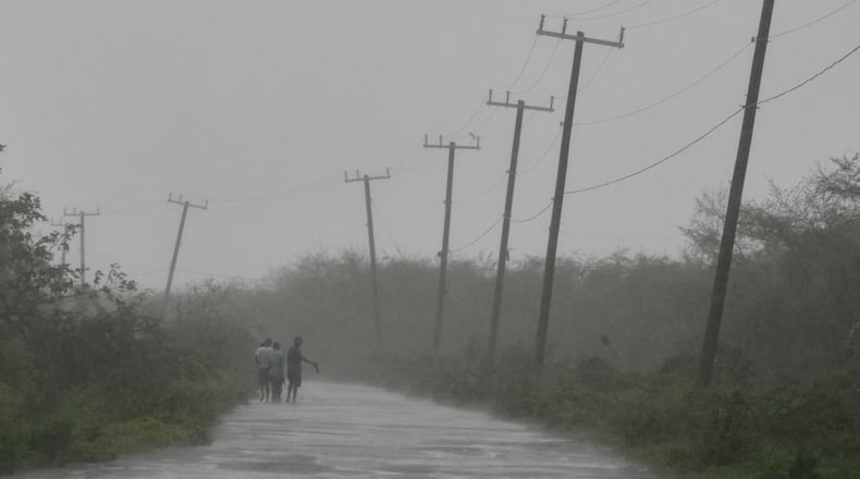 People walk along a road during the passing of Hurricane Melissa in Rocky Point, Jamaica, Tuesday, Oct. 28, 2025. (AP Photo/Matias Delacroix)