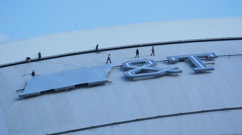 Workers cover signage on the exterior of AT&T Stadium, which will be named Dallas Stadium during the 2026 FIFA World Cup soccer tournament, as preparations continue at the venue, Tuesday, June 2, 2026, in Arlington. (AP Photo/LM Otero)
