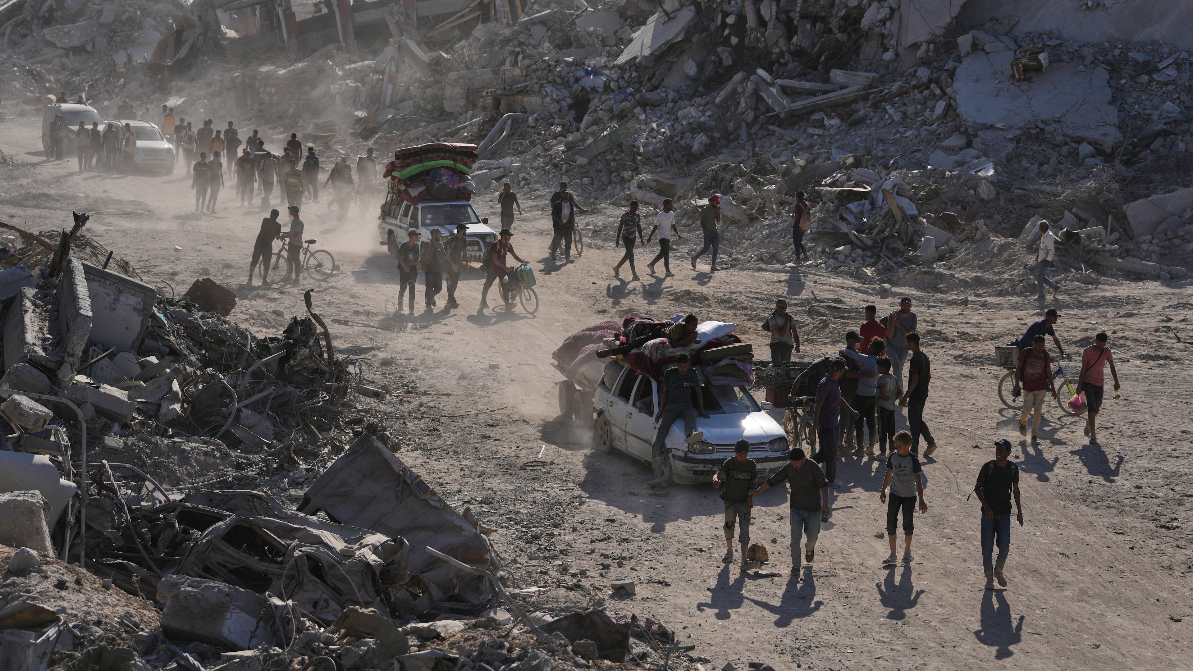 Displaced Palestinians with their belongings pass by destroyed buildings as they return to their homes in the Zeitoun neighborhood of Gaza City, Friday, Oct. 10, 2025, after Israel and Hamas agreed to pause their war and release remaining hostages. (AP Photo/Jehad Alshrafi)