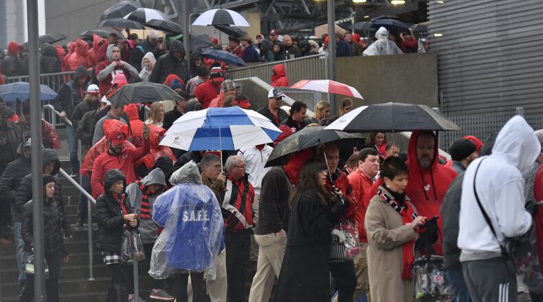 Fans stand in line to go through security in the rain outside Mercedes-Benz Stadium before College Football Playoff National Championship on Jan. 8, 2018.