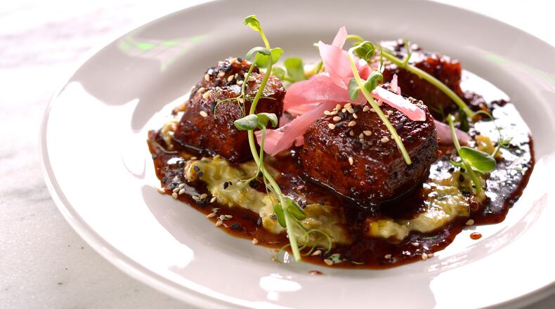 An order of Peppered Pork Belly at City Pharmacy brings fatty, salty chunks glistening with a sorghum glaze over a pool of creamed leeks. Photo courtesy City Pharmacy