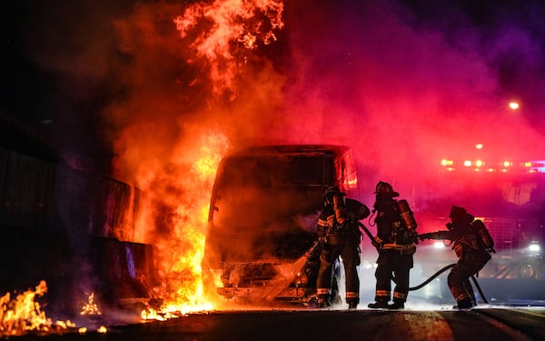 Firefighters work to extinguish flames pouring from a vehicle along I-75 South entering northwest Atlanta early Tuesday morning. (Ben Hendren for the AJC)